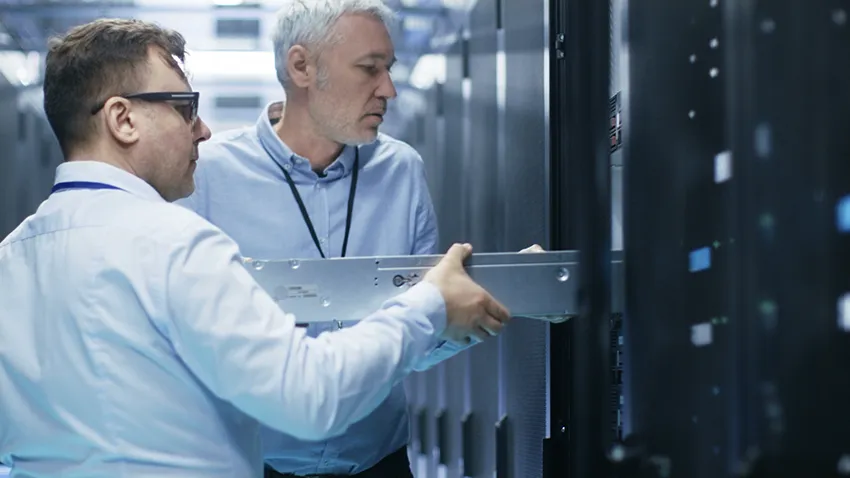 Technicians installing a server in a network rack inside the server room.